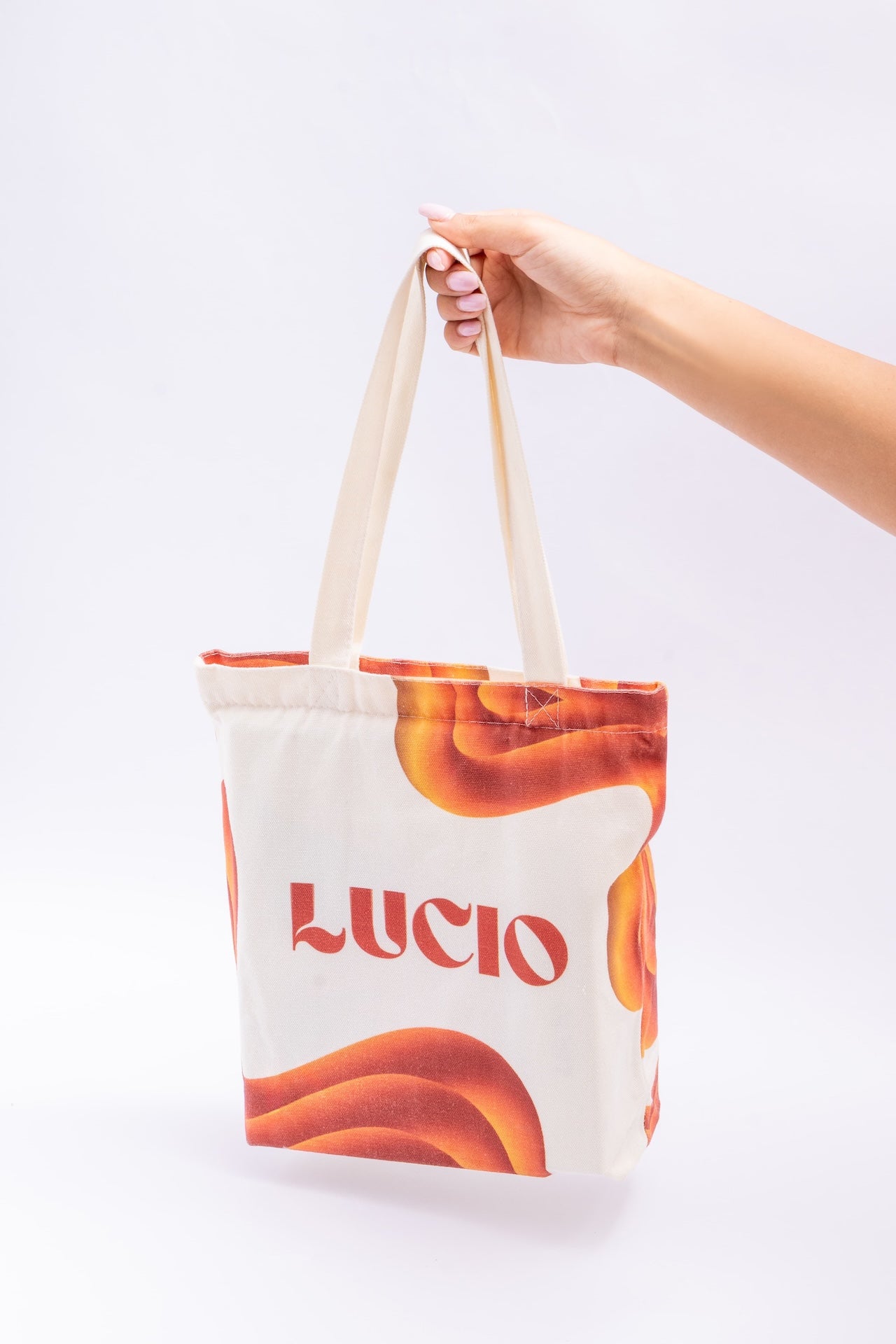 Tote bag with 'Lucio' branding held by a hand on a white background