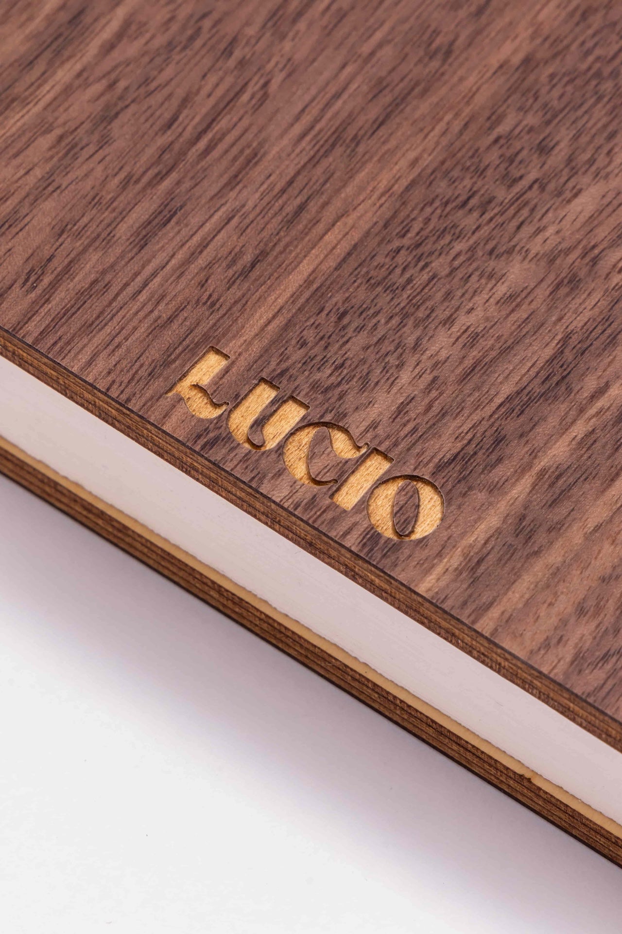 Wooden surface with 'Lucio' engraved in gold on a white background