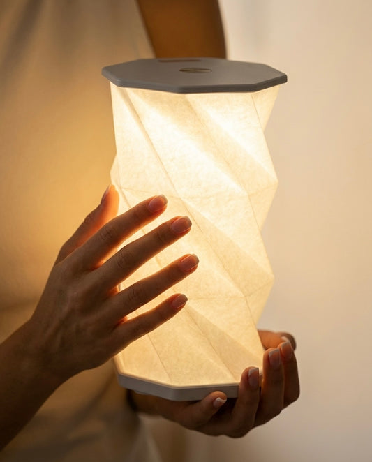 Hexagonal lamp held in hands with a soft glow